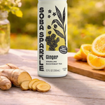 Sparklebuck Ginger Sparkling Buckwheat Tea can on a wooden surface with ginger root and oranges.