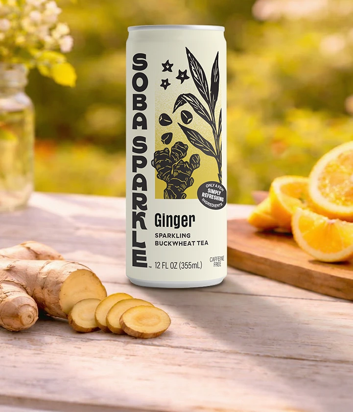 Sparklebuck Ginger Sparkling Buckwheat Tea can on a wooden surface with ginger root and oranges.